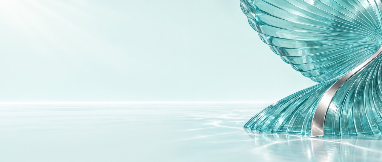 A material study photographed in bright daylight. A tall fan of clear turquoise glass fins rises on the right of the frame with a polished pearl silver ribbon curving through it, standing in a shallow film of still water. The left of the frame is empty pale mint.