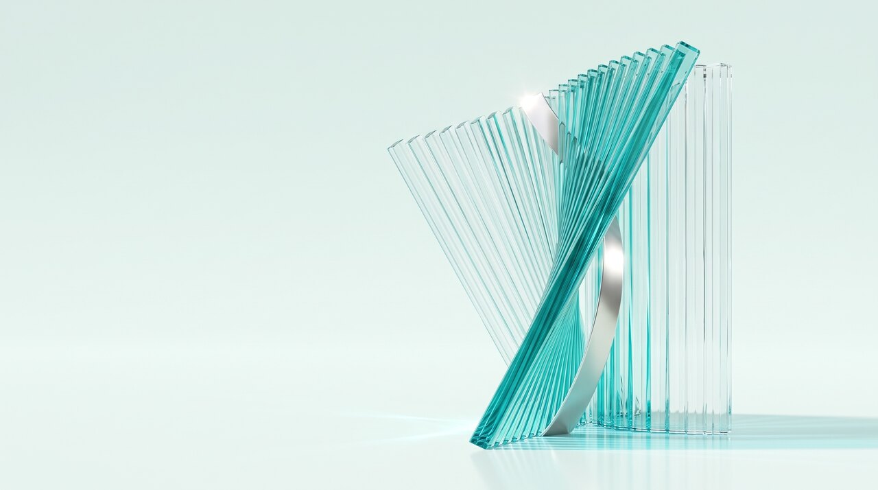 A material study in bright daylight. A fan of clear turquoise glass blades opens from a low point and sweeps up to the right, crossed by a polished pearl silver ribbon, with a straight rank of upright glass fins standing behind it like a wall.